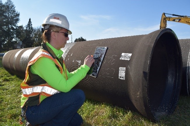 An inspector uses a mobile device to scan the barcode on a stockpiled pipe.